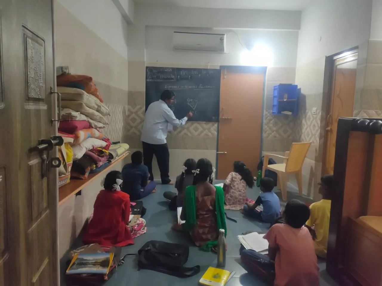 A tutor teaching a group of children at the Kuteer