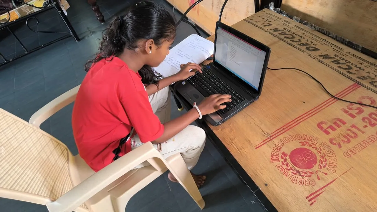 A student working on a laptop in the computer class