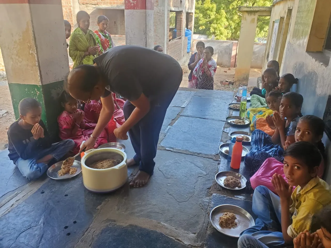 Children served a hot meal, seated in a row with their plates