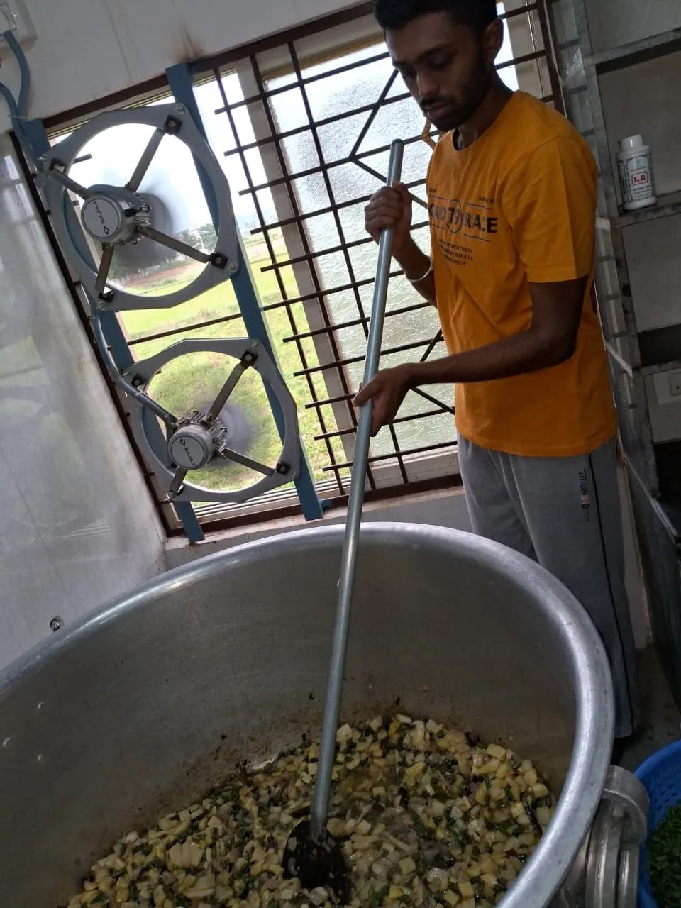 A volunteer stirring a large vessel of curry in the Kuteer kitchen