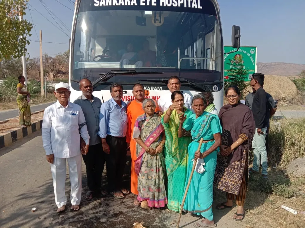 Patients and volunteers beside the Sankara Eye Hospital bus