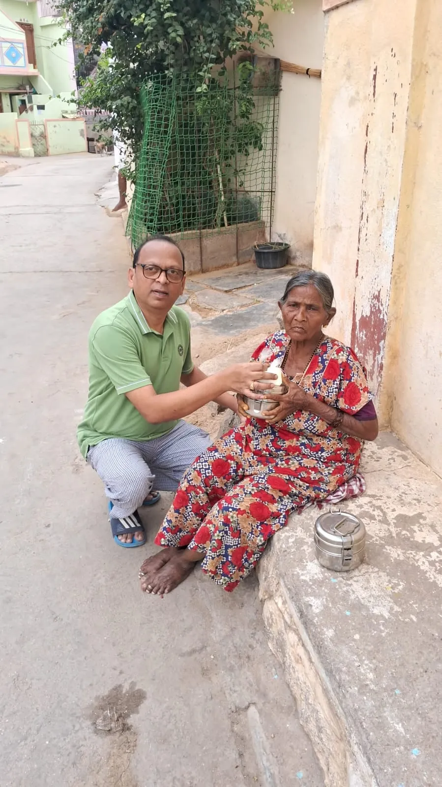 A meal being handed to an elderly woman seated on the ground