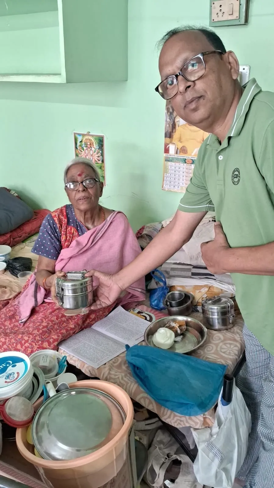 A volunteer sitting with an elderly woman during a Narayana Seva home visit