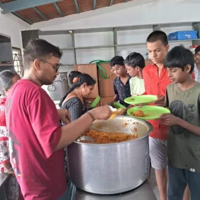 Children being served from a large vessel at the Kuteer